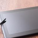 Blank digital tablet with a stylus resting on the side lying on a wooden desk in an oblique angle view